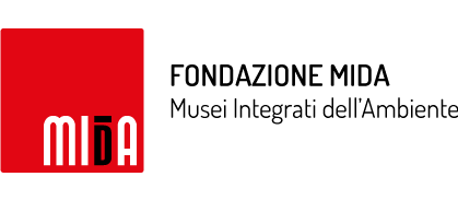 Logo MIDA: la scritta MIDA in caratteri bianchi moderni si trova all'interno di un quadrato rosso. La lettera 'D' della scritta 'MIDA' è parzialmente colorata di nero con un trattino orizzontale sopra la lettera. Accanto al logo sulla destra vi è la scritta in nero Fondazione Mida e immediatamente sotto appare la scritta Musei integrati dell'Ambiente.